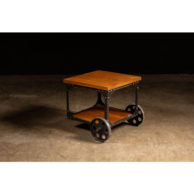 Contemporary oak and steel rolling side table. This industrial-inspired piece features two golden oak shelves for storage...