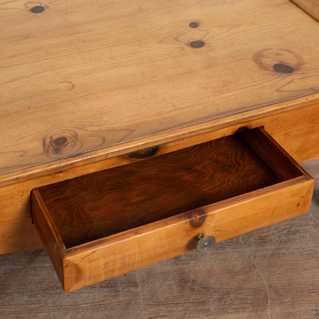 Large pine coffee table with raised edge and two drawers fitted with brass pulls. Scalloped skirt, turned legs, and warm...