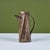 Geometric ceramic pitcher with a faux metal painted exterior. The pitcher features curved handle, spout and lid....
