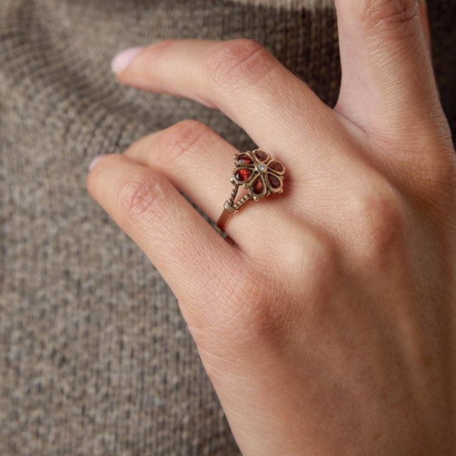 A beautifully romantic Victorian flower ring, this 9 karat rose gold treasure blossoms with rich crimson garnets arranged...