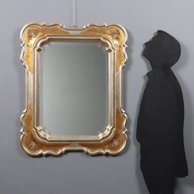 Gilded wood mirror featuring faux silver and faux gold leaf workmanship, enriched with painted floral details positioned...
