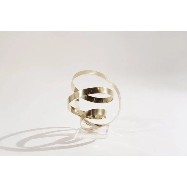 Signed ribbon sculpture titled "Impatience "by American artist, Dan Murphy, circa 1979. Gleaming anodized gold-tone...