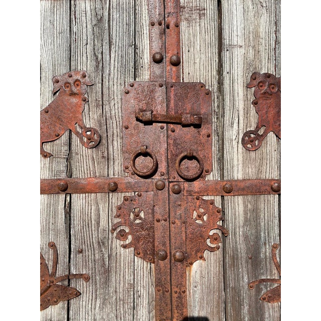 Antique Mongolian double doors or entry gate crafted from thick weathered pine with extensive hand-forged iron strapwork...