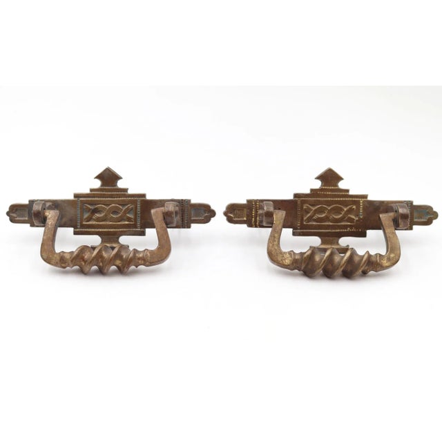 Antique Eastlake style drawer pulls made of brass with a patina finish. Each pull features intricate carvings and twisted...