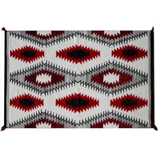 A striking early 20th century Navajo blanket with a bold all-over diamond pattern woven in crimson, white, gray, and black...