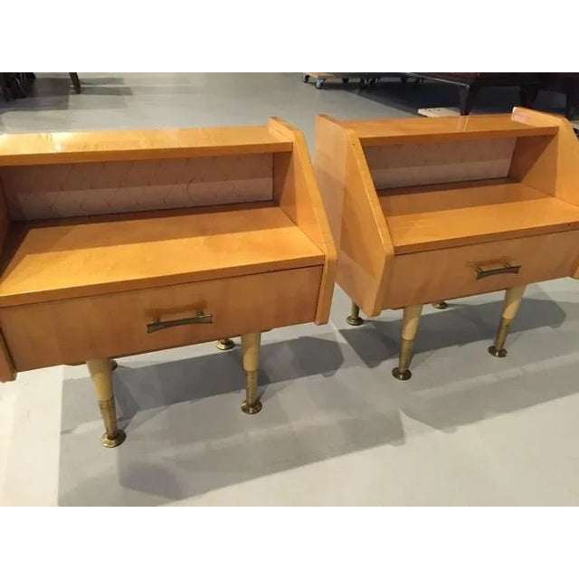A beautiful pair of French Art Deco sycamore nightstands with one drawer. The fabric on the back of the table has a cut...