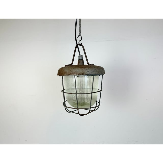 Industrial factory hanging lamp made by Polam Wilkasy in Poland during the 1960s.It features a cast iron top, a striped...