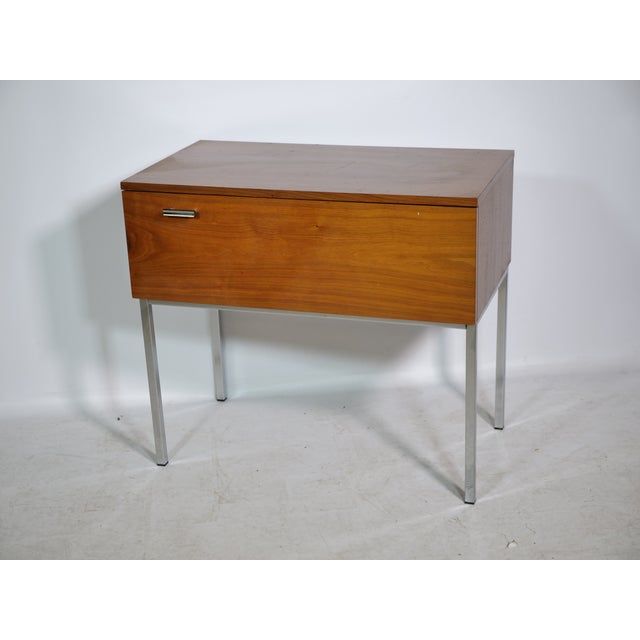 Vintage teak and chrome chest of drawers from the 1960s. Features a front-mounted drop-down door with storage space. Tall,...