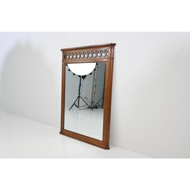 A finely crafted cherry wood wall mirror by Kindel Furniture Company, featuring a warm hand-finished frame with...