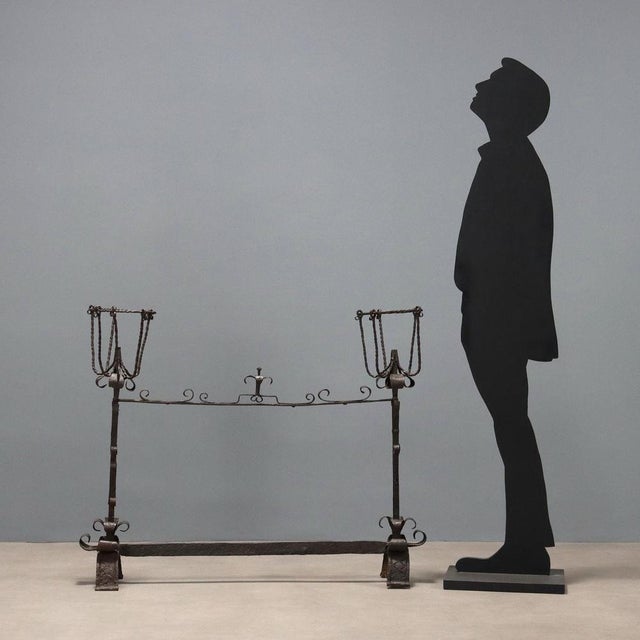 Wrought iron fireplace andiron with curlicue decorations. This piece is attributed to the mentioned designer/maker. It has...