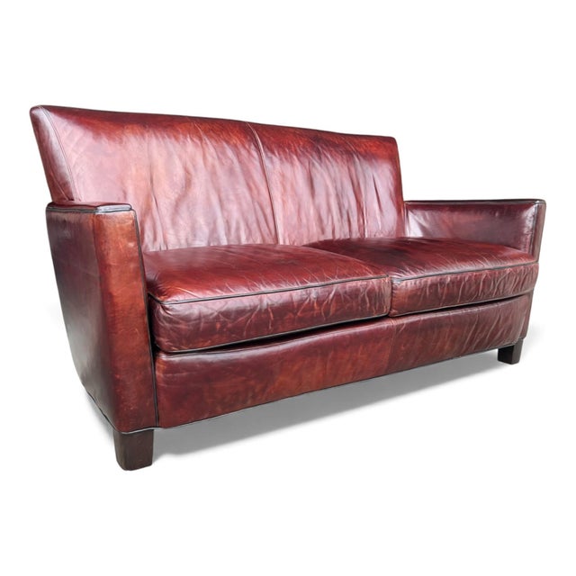 This vintage burgundy leather sofa features gently sloped arms, tailored lines, and piped detailing. Generously padded...