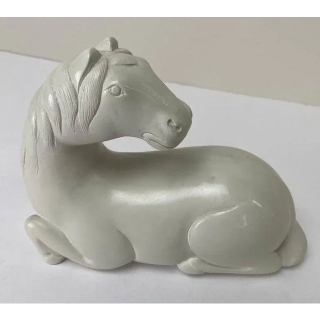An equestrian sitting white horse sculpture, crafted with exquisite precision and care. Handcrafted from clay, this...