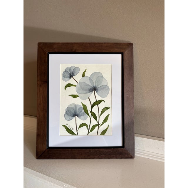 Soft, translucent blue blossoms rise on slender stems. Layered washes create a gentle sense of movement, while the...