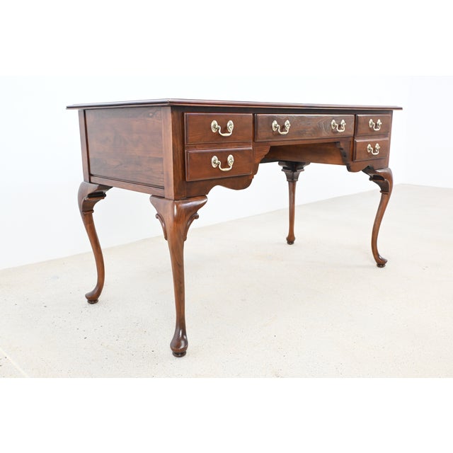 Solid cherry Queen Anne–style writing desk by Ethan Allen, featuring three drawers with polished brass pulls....