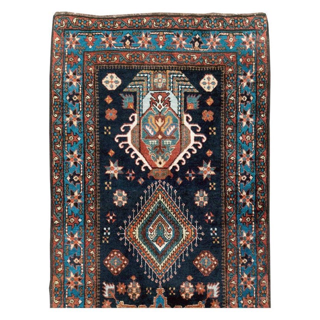 This early 20th-century Persian Heriz long runner presents a richly detailed geometric-floral composition across a deep...