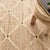 A large ivory latticework pattern emerges from the relaxed natural jute kilim weave foundation with a punctuating charcoal...