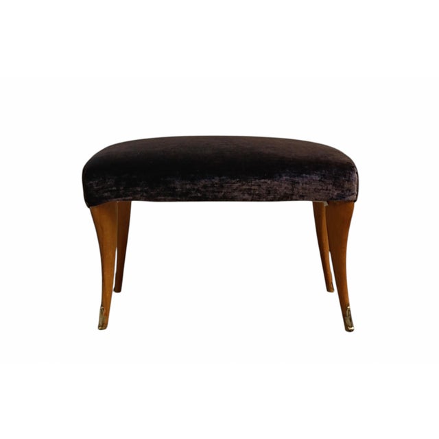 An Italian designer stool from the 1950s, characterised by a rounded seat and four slender wooden legs with brass finials....