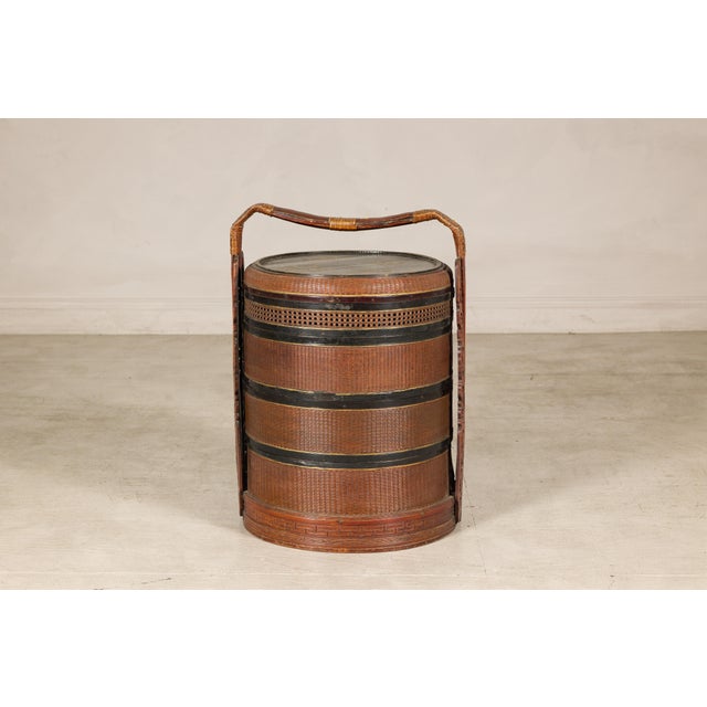 This vintage Chinese carrying basket features a cylindrical form crafted from tightly woven rattan and bamboo with a...