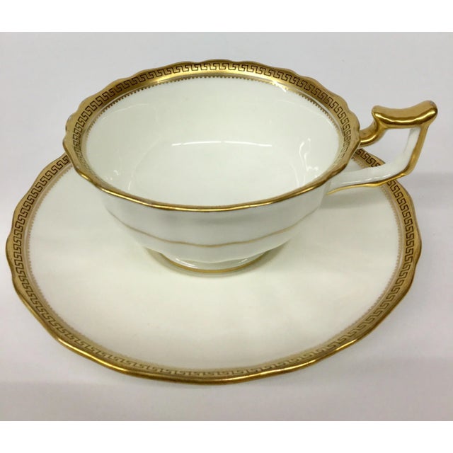 Pristine cup and saucer by Cauldon England. Trimmed in 24 K gold on bone porcelain. Scalloped edges and Greek Key Design....