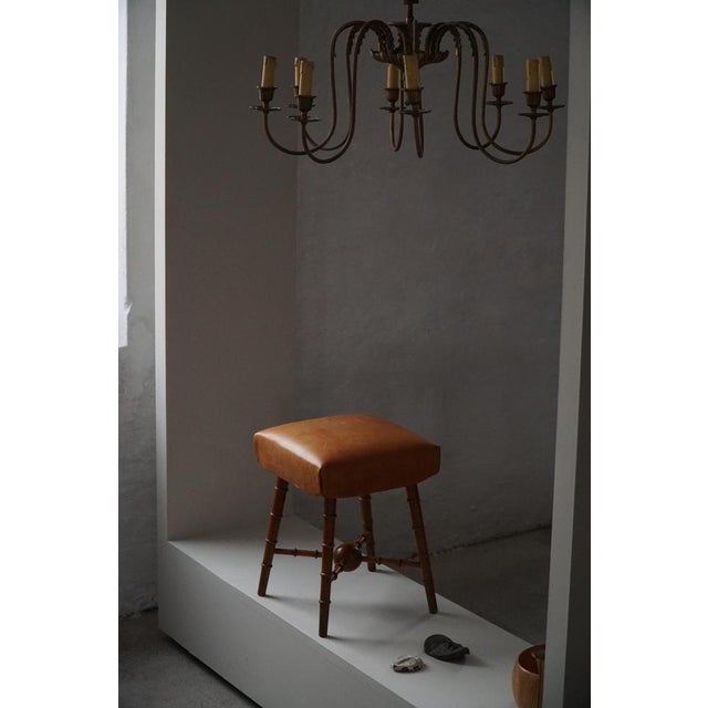 A charming mid 20th-century stool, crafted with finely turned wooden legs and stretchers and topped with a softly...