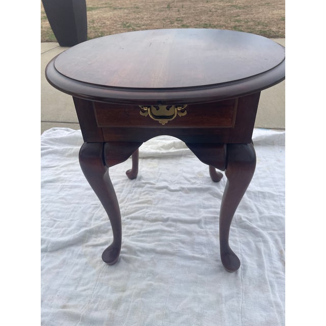 This Queen Anne Style side table features characteristic Queen Anne elements including cabriole legs, oval top, and a...