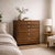 A compact vintage mid-century chest of drawers with warm walnut-toned grain, six flush-front drawers, and understated...