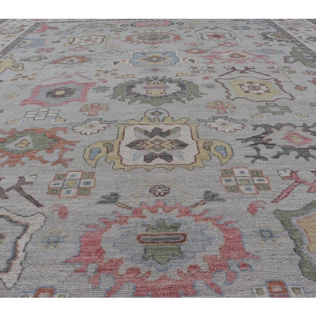 The border and field are covered in floral-like motifs filled with colors such as pink, green, gold, teal and red-oranges...