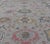 The border and field are covered in floral-like motifs filled with colors such as pink, green, gold, teal and red-oranges...