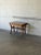 This vintage coffee table features an inset ceramic tile top with stylized floral motifs set within a rich oak frame....
