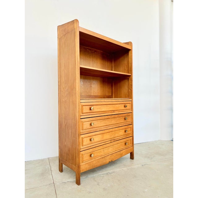 A 1940s-50s solid oak bookcase/chest of drawers, featuring two open shelves and four drawers with molded fronts and round...