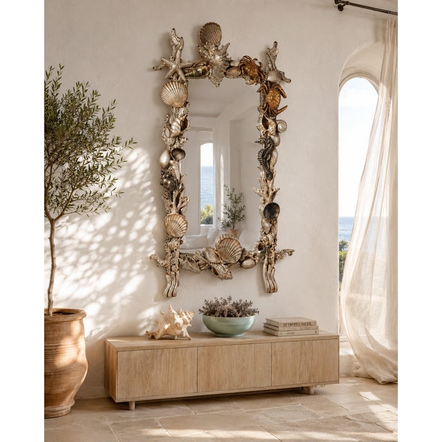 A large Italian wall mirror in Grotto style, crafted from painted hand-carved wood with richly carved relief decoration....