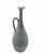 A pitcher-shaped vase with a handle, crafted from ceramic with a distinctive rough, textured finish that has a chalky...