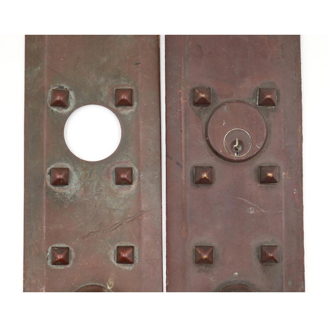 Arts & Crafts style studded entry door back plates made of bronze with lock inserts. Inscribed on the back. The original...