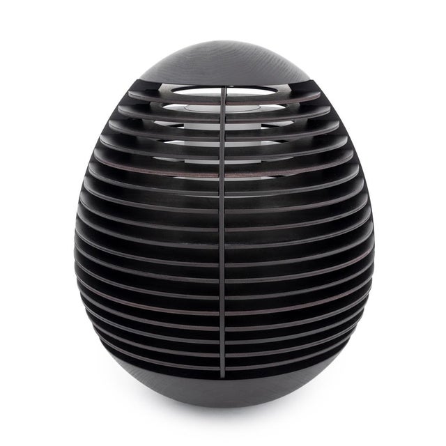 The Tocco lamp features a minimalist, egg-shaped design with an oak wood body and wenge finish, complemented by a glass...