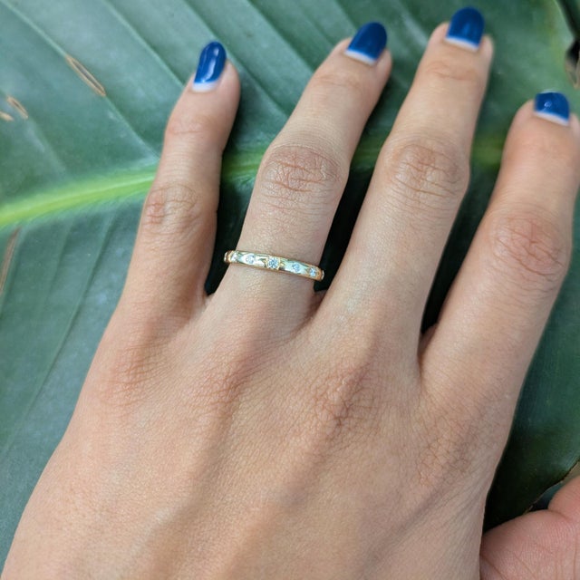 This elegant floral-inspired diamond band features a delicate arrangement of round brilliant diamonds set in a star-floral...