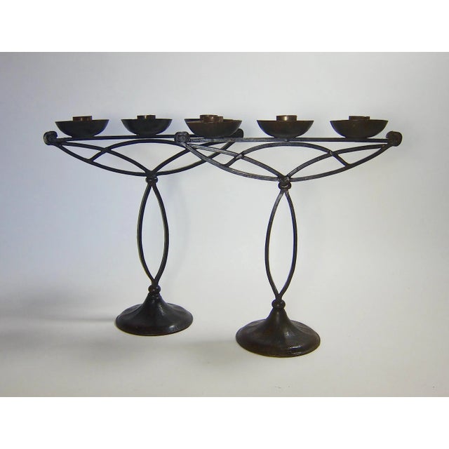 An imposing matched pair of three-armed candle holders hand forged in black iron during the Arts and Crafts period in...