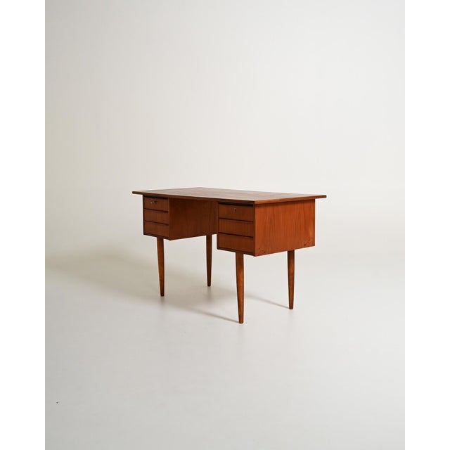 Teak desk with six drawers distributed across two side modules and tapered beech legs. Scandinavian production, 1960s. The...