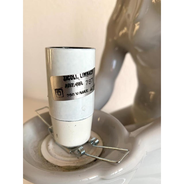 This stunning Art Deco Revival table lamp from the 1980s features a beautifully sculpted blue porcelain figure of a seated...