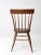 This is an antique farmhouse chair. The primitive dining or side chair features a plank seat, spindle back, and turned legs.