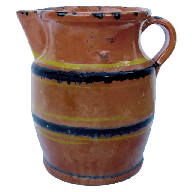 Charming large glazed redware pitcher in earthy terracotta hues featuring hand painted black & yellow horizontal banding...