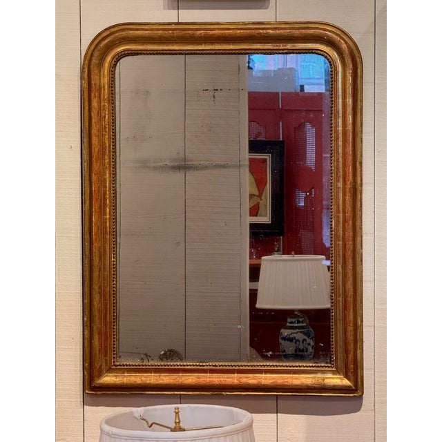 19th century Louis Philippe giltwood mirror with rounded upper corners, incised foliate decoration and a beaded inner...