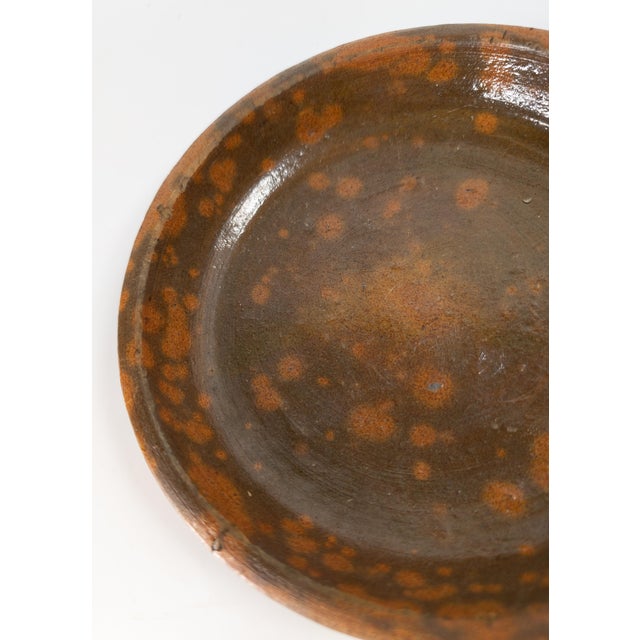 We are selling this simple 19th Century redware pie dish. This pie dish has manganese glaze with splattered spotted glaze...