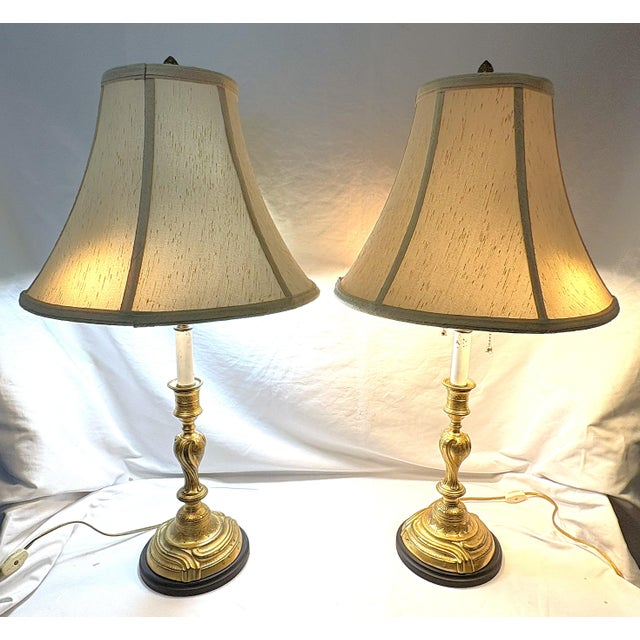 Timeless pair of French Art Nouveau candlestick lamps from the early 20th century. They're made of embossed brass with...