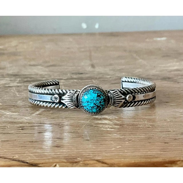 This vintage sterling silver cuff bracelet showcases traditional Southwestern silversmithing techniques, its substantial...