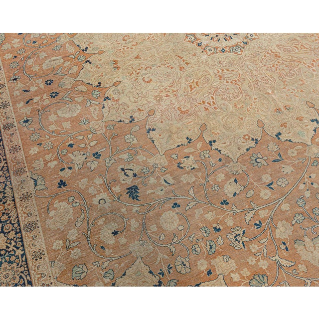 A hand-knotted wool antique Persian Tabriz rug dating back to circa 1900. The main field features a large floral...