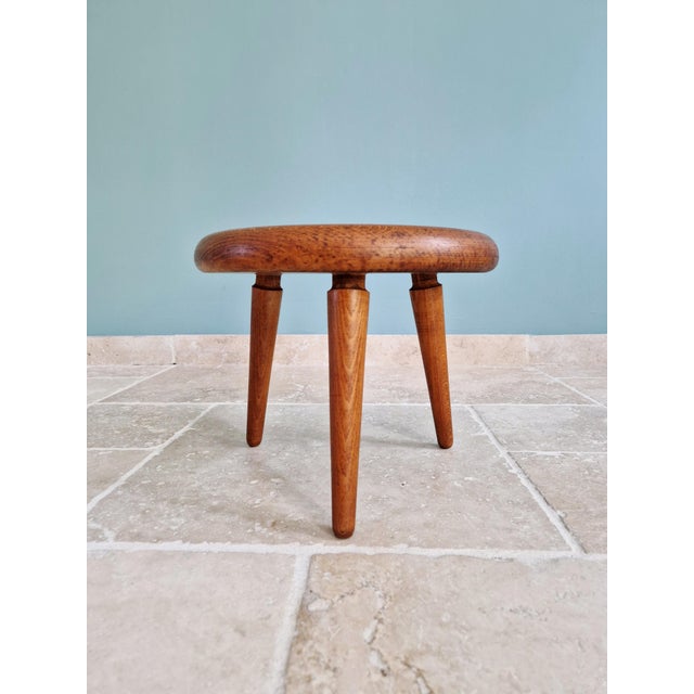 Modernist tripod stool in solid wood, made in the 1950s-60s. It features a thick, circular seat with rounded edges,...