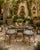 A charming vintage bistro table featuring a generous round glass top supported by an elegant wrought iron frame....