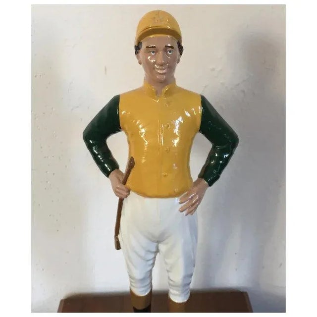 Vintage heavy iron statue of a lawn jockey dressed in silks, cap, jodhpurs, boots and carrying a riding crop. Mounted on a...