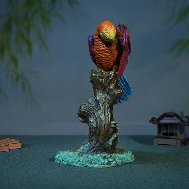 This vibrant brass figurine features a highly detailed parrot perched upon a sculpted tree trunk base. The bird is crafted...