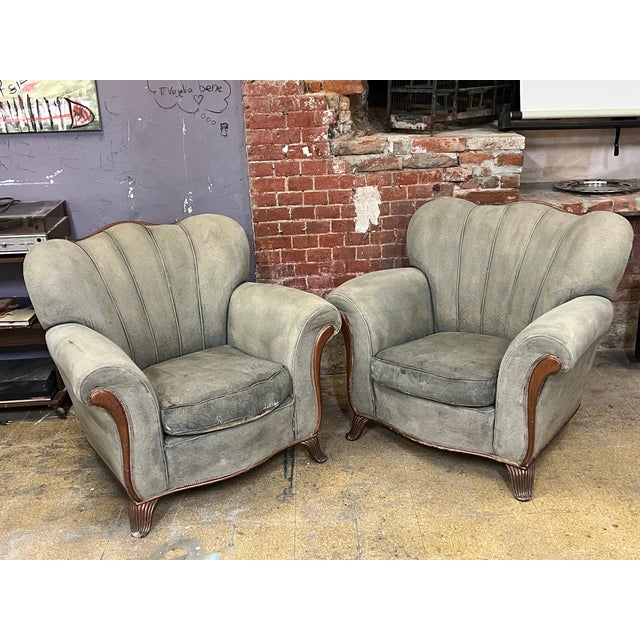 Pair of vintage to be reupholstered armchairs featuring sculpted scalloped backrests, rolled arms with wood accents, and...
